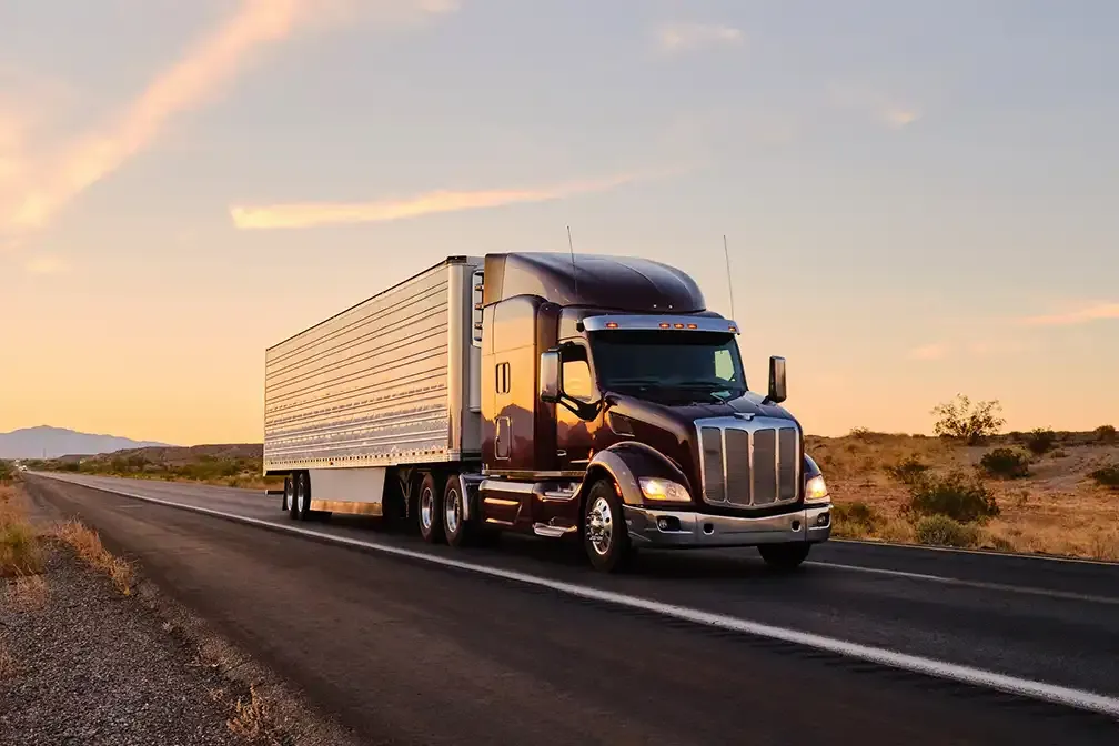 Tractocamión con remolque refrigerado en una autopista al atardecer